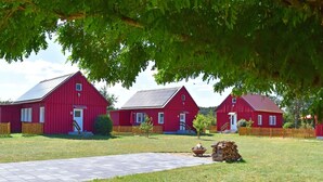 A red barn with a paved driveway and a stack of firewood.
