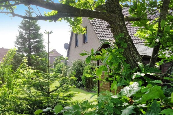 A house with a sloped roof, surrounded by lush greenery and trees.