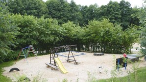 Un parque infantil con columpios, un tobogán y una casita de juegos.