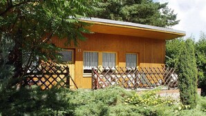 Una cabaña de madera con cerca de celosía, número 25, rodeada de vegetación densa.