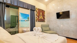 Ein Hotelzimmer mit einem Bett, einem Sessel, einem Fernseher und einem Wandgemälde.
