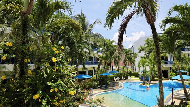 Ein Poolbereich eines Resorts, umgeben von Palmen und einem Gebäude mit Balkonen.