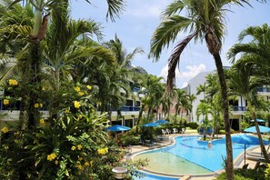 A resort pool area surrounded by palm trees and a building with balconies. - 5 Bedroom Villa Near Kamala Beach (Kamala)