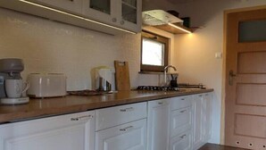 A kitchen with white cabinets, a wooden countertop, a coffee maker, a toaster, and a window above the sink. - Holiday home with jacuzzi and private garden (Gizycko)