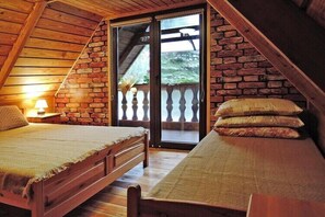 A bedroom with two beds, a wooden ceiling, and a brick wall.
