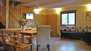 A wooden interior with a dining table, chairs, a sofa, and a TV mounted on the wall. - Holiday home with jacuzzi and private garden (Gizycko)