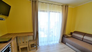 A compact living space with a kitchenette, a sofa, a dining table, and a chair.