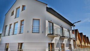 A modern multi-story residential building with balconies, large windows, and a flat roof.