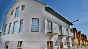 Un immeuble résidentiel moderne à plusieurs étages, doté de balcons, de grandes fenêtres et d’un toit plat.