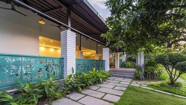 Un edificio moderno con una galería techada, plantas verdes y un césped bien cuidado.