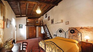 A bedroom with a bed, wooden furniture, a staircase, and a chandelier. - Casa Mare Holiday in Vallugola (Vallugola)