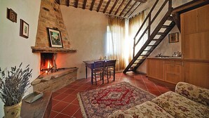 A cozy living room with a fireplace, a wooden staircase, and a dining area. - Casa Mare Holiday in Vallugola (Vallugola)