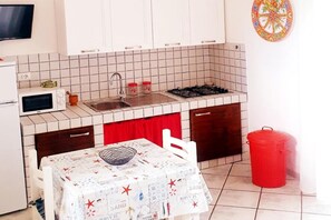 Une petite cuisine équipée d’un four à micro-ondes, d’un évier, d’une cuisinière et d’une table recouverte d’une nappe.