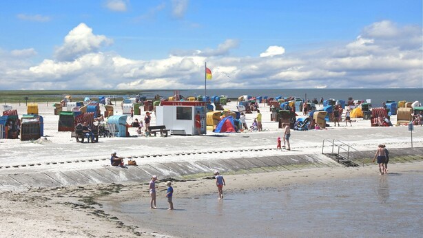 Een strand met vele kleurrijke strandhuisjes en een vlag.