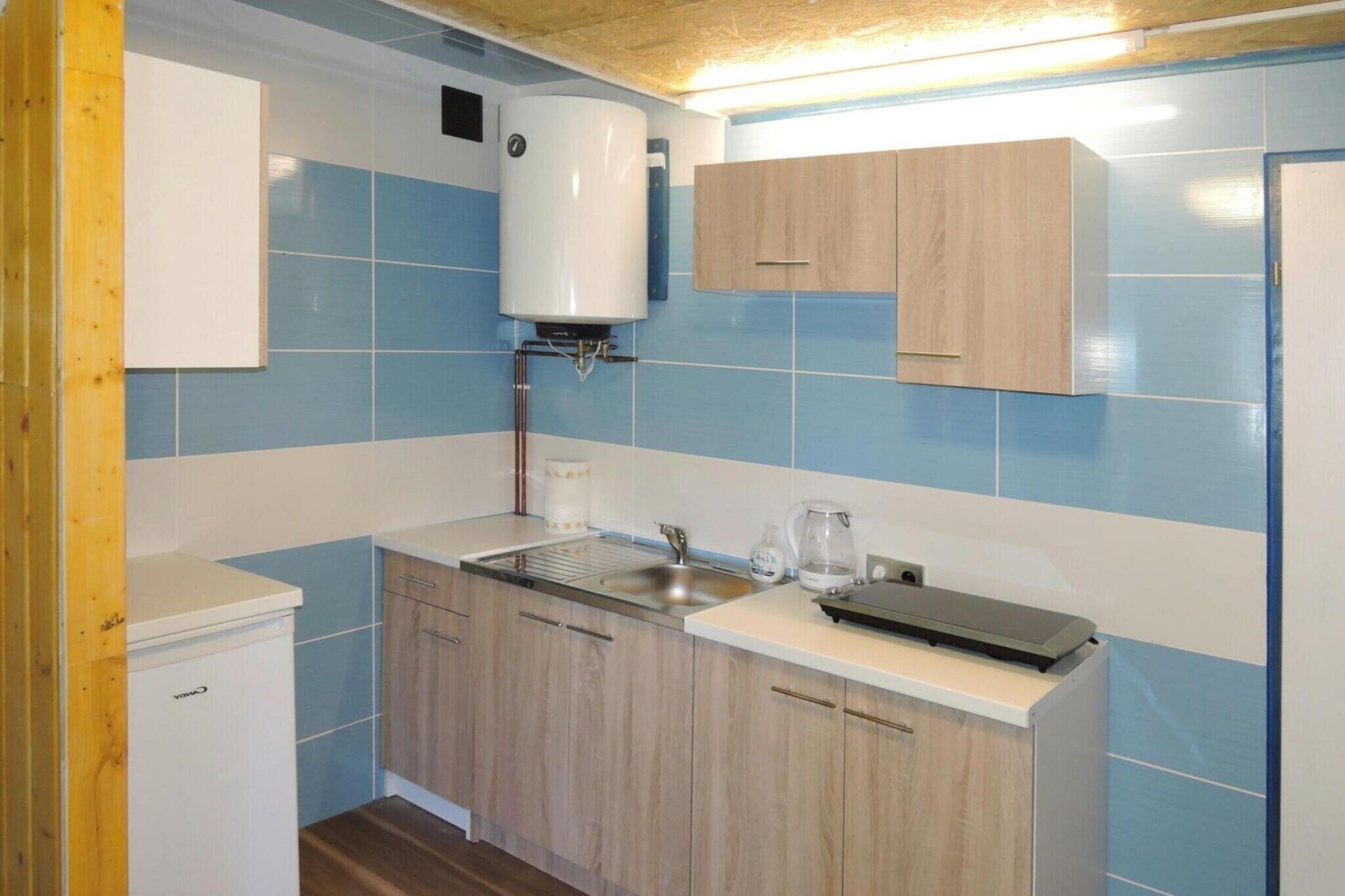 A compact kitchen with a built-in water heater, a sink, and a coffee maker.