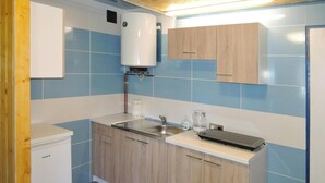 Una cucina compatta con scaldacqua integrato, lavandino e macchina da caffè.