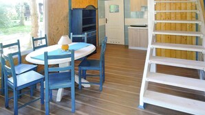 Una stanza con pavimento in legno, un tavolo rotondo con sedie, una porta bianca e una scala in legno.