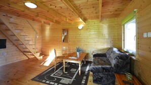 L’intérieur d’un chalet en bois comprend un coin repas, un canapé, un escalier et une fenêtre.