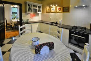 A kitchen with a dining table, chairs, a stove, and a sink. - Large holiday villa with fireplace and garden (Polanow)
