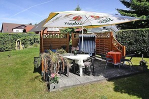 Enjoy al fresco dining in a serene garden setting with a seating area under a shaded umbrella.