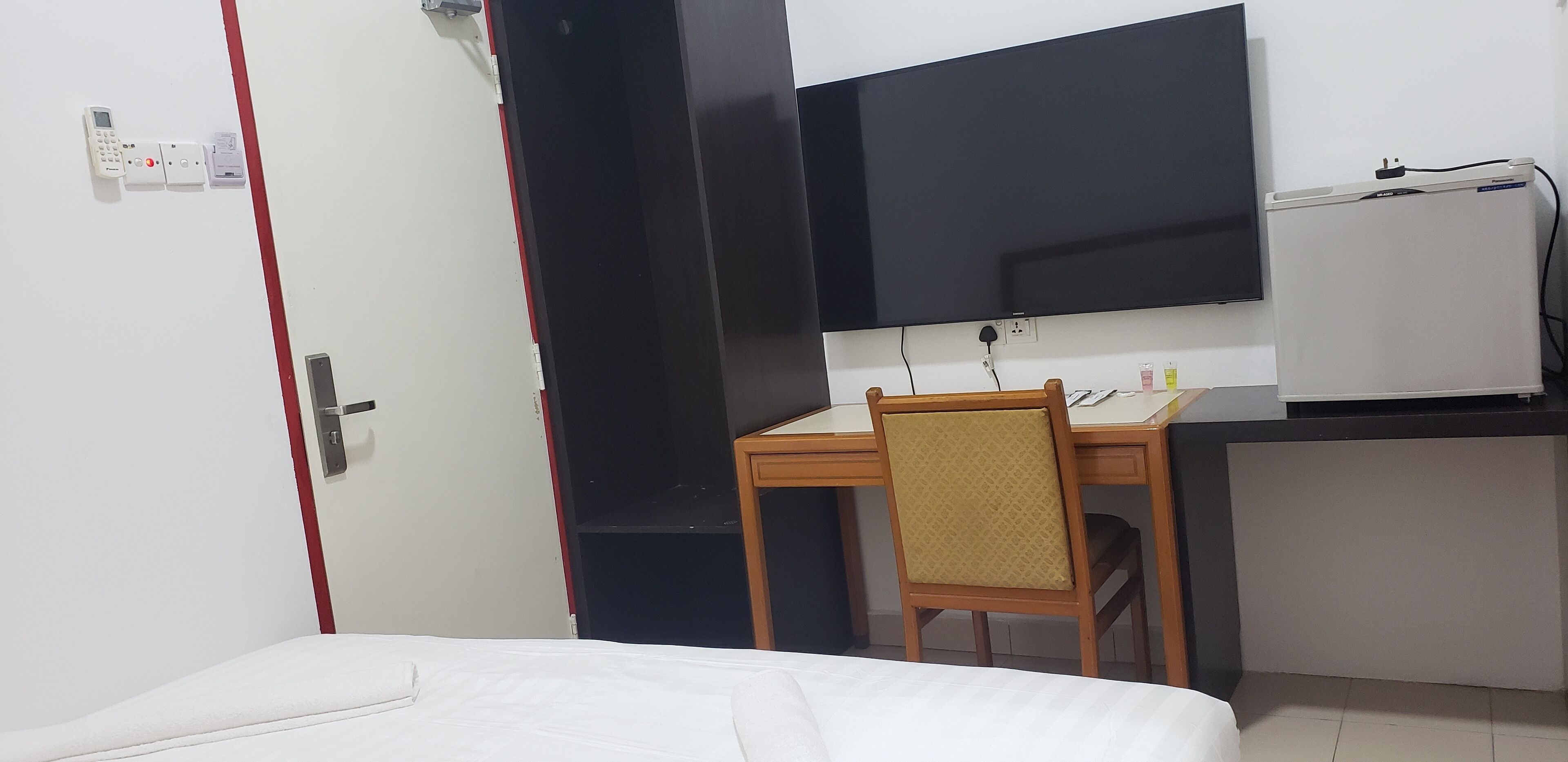 Une chambre d’hôtel équipée d’un lit, d’un bureau avec une chaise, d’une télévision et d’un réfrigérateur.
