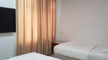 A small, simple room with a bed, a TV mounted on the wall, and a curtain.
