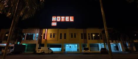 A hotel with a prominent 'HOTEL' sign, multiple parking spaces, and a gated entrance.