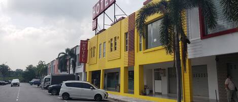 A hotel with a yellow facade and a red sign indicating it is a hotel.
