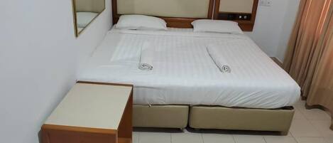 A neatly made bed with a headboard, a bedside table, and a small cabinet.
