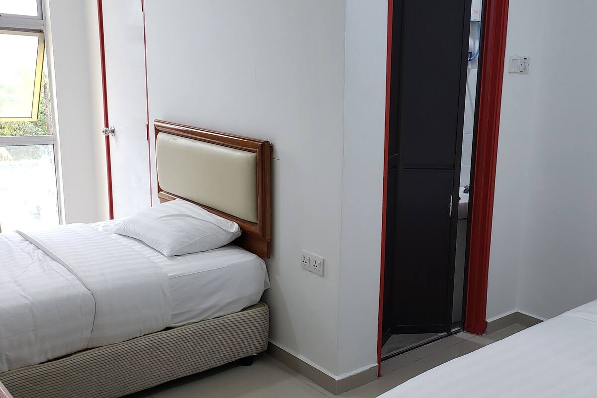 Habitación de hotel con dos camas, una puerta y una ventana.