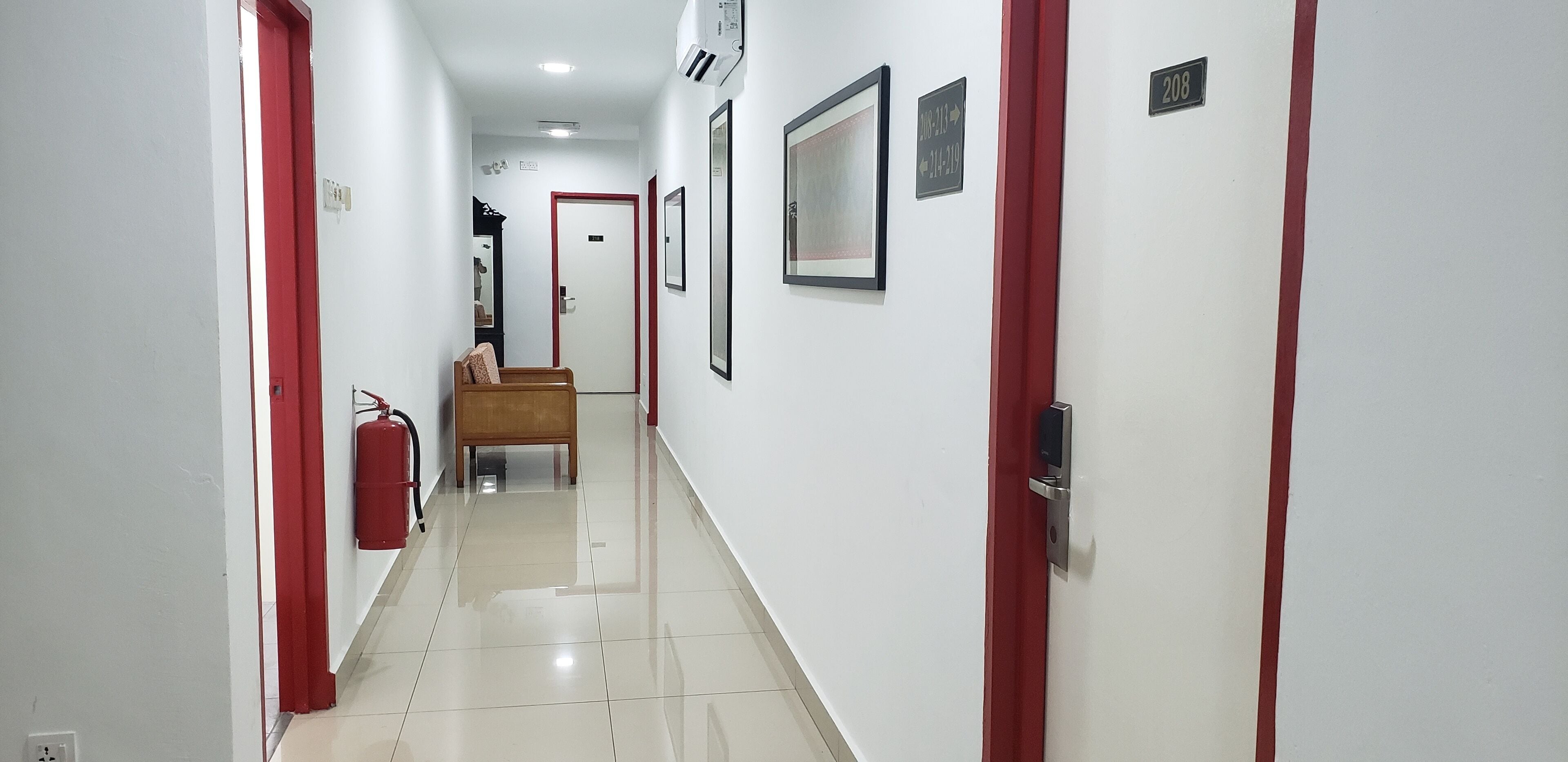 A hallway with white walls, red doors, and a fire extinguisher on the left.