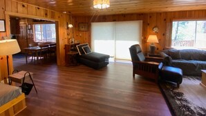 A wooden interior with a dining area, a sofa, and a lamp.