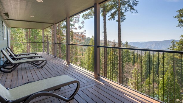 A wooden deck with two lounge chairs and a covered area, overlooking a forest and mountains. - Panoramic Paradise (Yosemite National Park)
