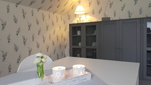 A dining area with a table, chairs, a vase with flowers, and a tray with candles. - Ferienhaus mit drei Bädern in Dornumersiel (Dornumersiel)