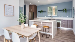 Eine moderne Küche mit einer zentralen Kochinsel, Holzschränken und einem Edelstahl-Kühlschrank.