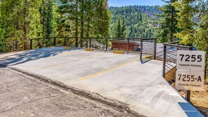 Ein Parkplatz mit Betonbefestigung, markierten Stellplätzen und einer Geländer. Schilder zeigen '7255 Yosemite Parkway' und '7255-A Yosemite Parkway'.