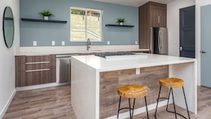 A modern kitchen with a central island, wooden cabinets, and two bar stools. - Apex Yosemite West (Yosemite National Park)