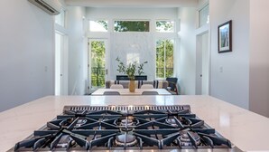 A modern kitchen with a large island, a gas stove, and a seating area with a sofa and a vase of plants. - Apex Yosemite West (Yosemite National Park)