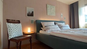 A bedroom with a bed, a chair, a bedside table with a lamp, and wall art. - Vacation apartment Belchenblick  (Staufen im Breisgau)