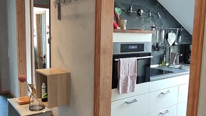 A modern kitchen with a built-in oven, a coffee machine, and a hanging utensil rack. - Vacation apartment Belchenblick  (Staufen im Breisgau)