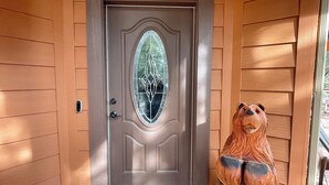 Puerta de madera con un panel de vidrio y una escultura de oso a la derecha.