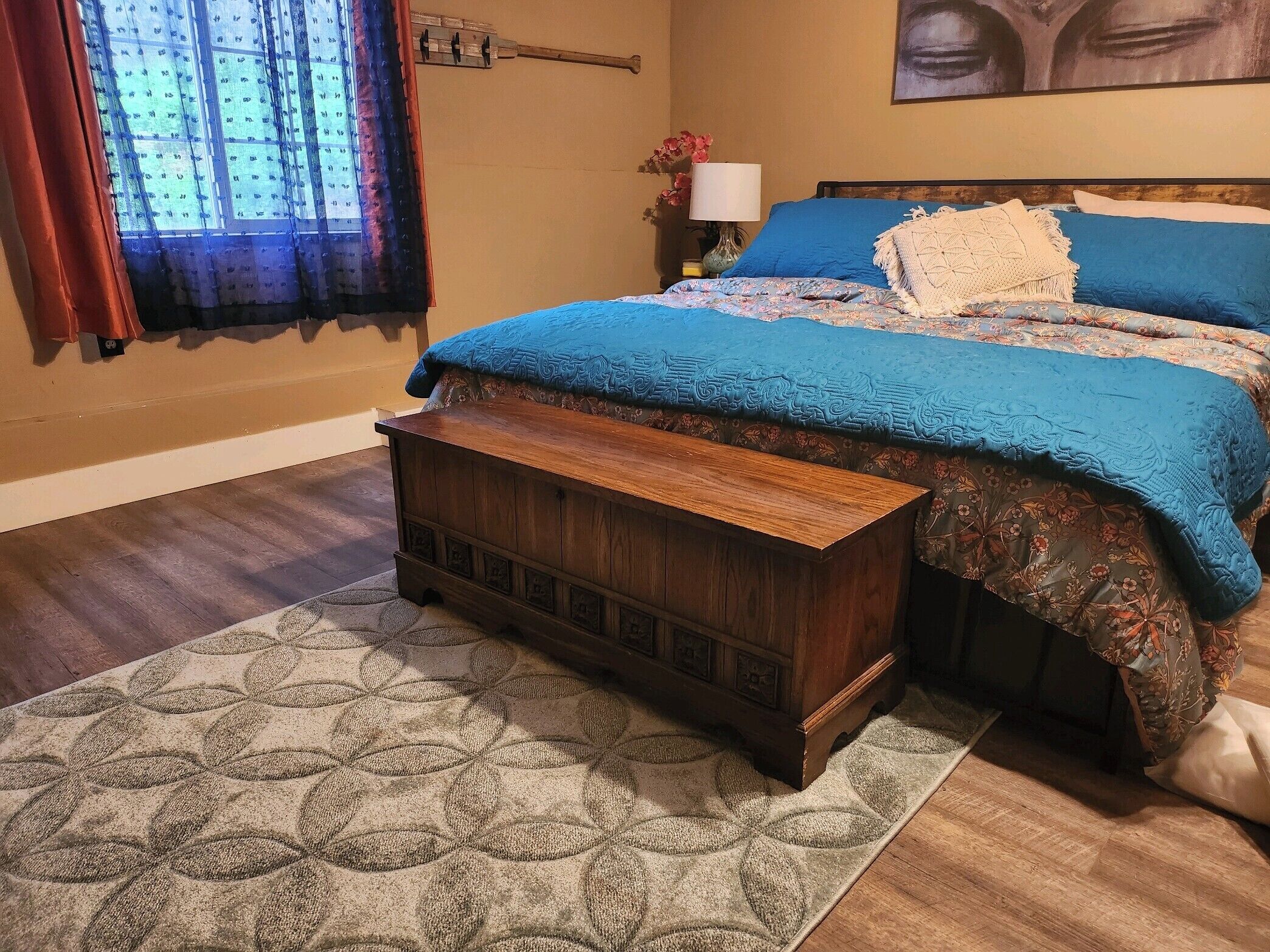 Una camera da letto con un comò in legno, un tappeto decorato e un letto con biancheria azzurra.