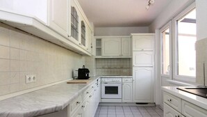 A kitchen with white cabinets, a stove, and a coffee maker. - Ferienhaus Yvonne in Wendorf im Bernstein Resort (Wendorf)