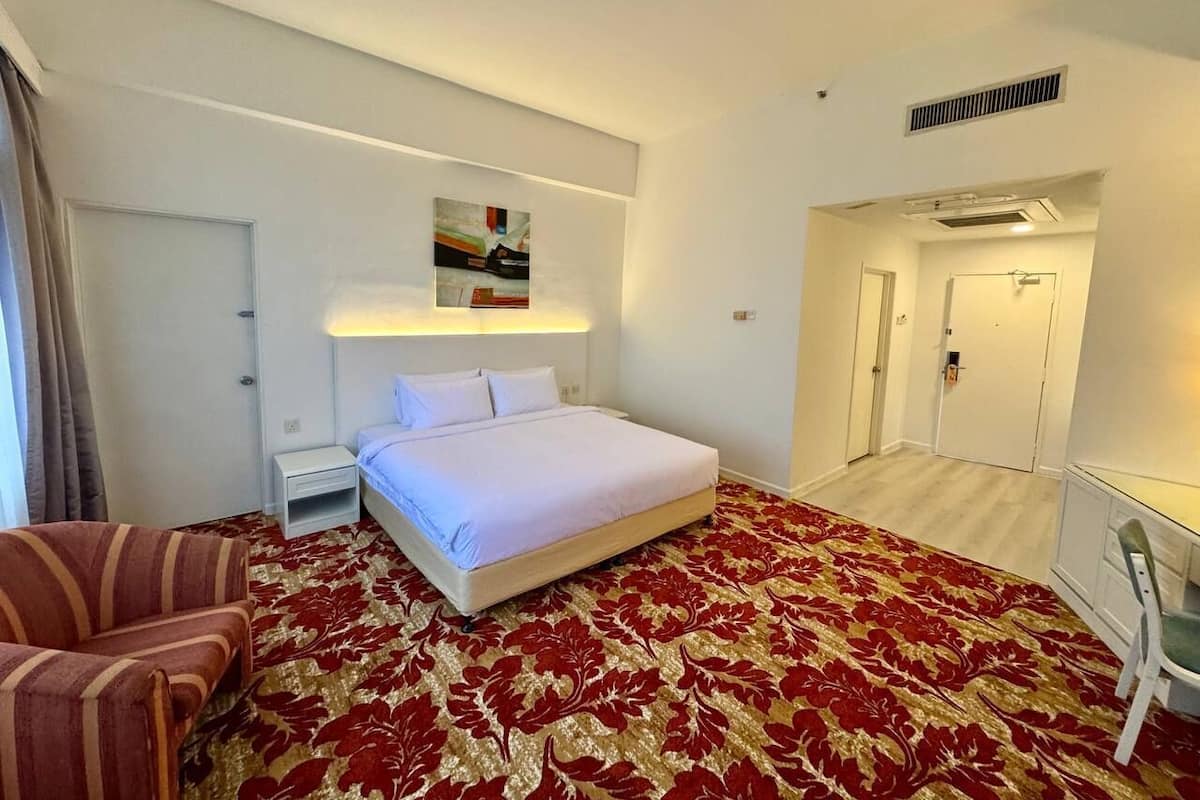Une chambre d’hôtel comprenant un lit, une table de chevet, une chaise, un bureau et une porte donnant sur une autre pièce.