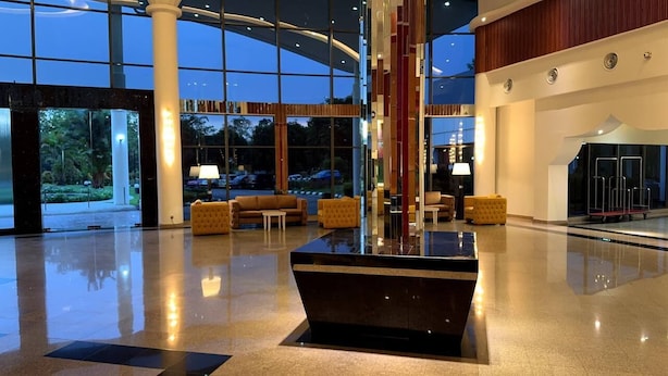 En rymlig entréhall med en central, svart receptionsdisk, bekväma sittgrupper och stora fönster med utsikt över omgivningarna.