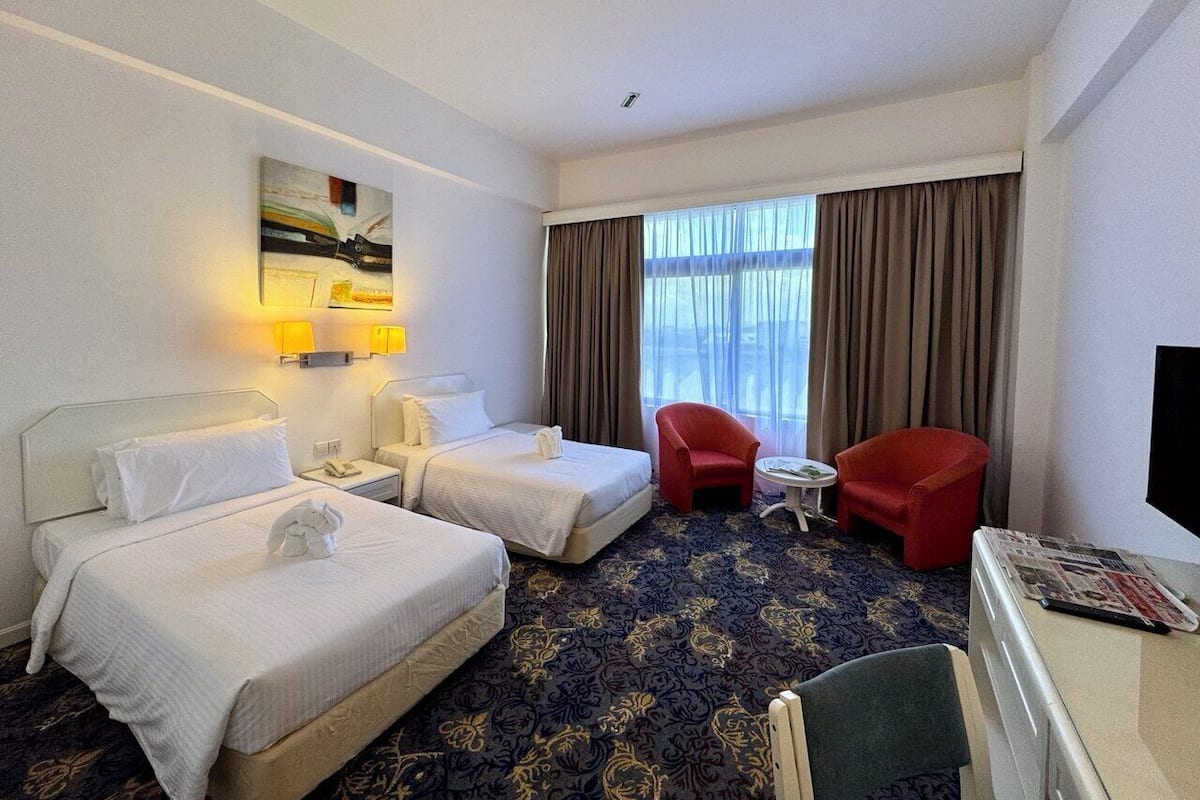 Une chambre d’hôtel avec deux lits, un bureau, une chaise et un téléviseur.