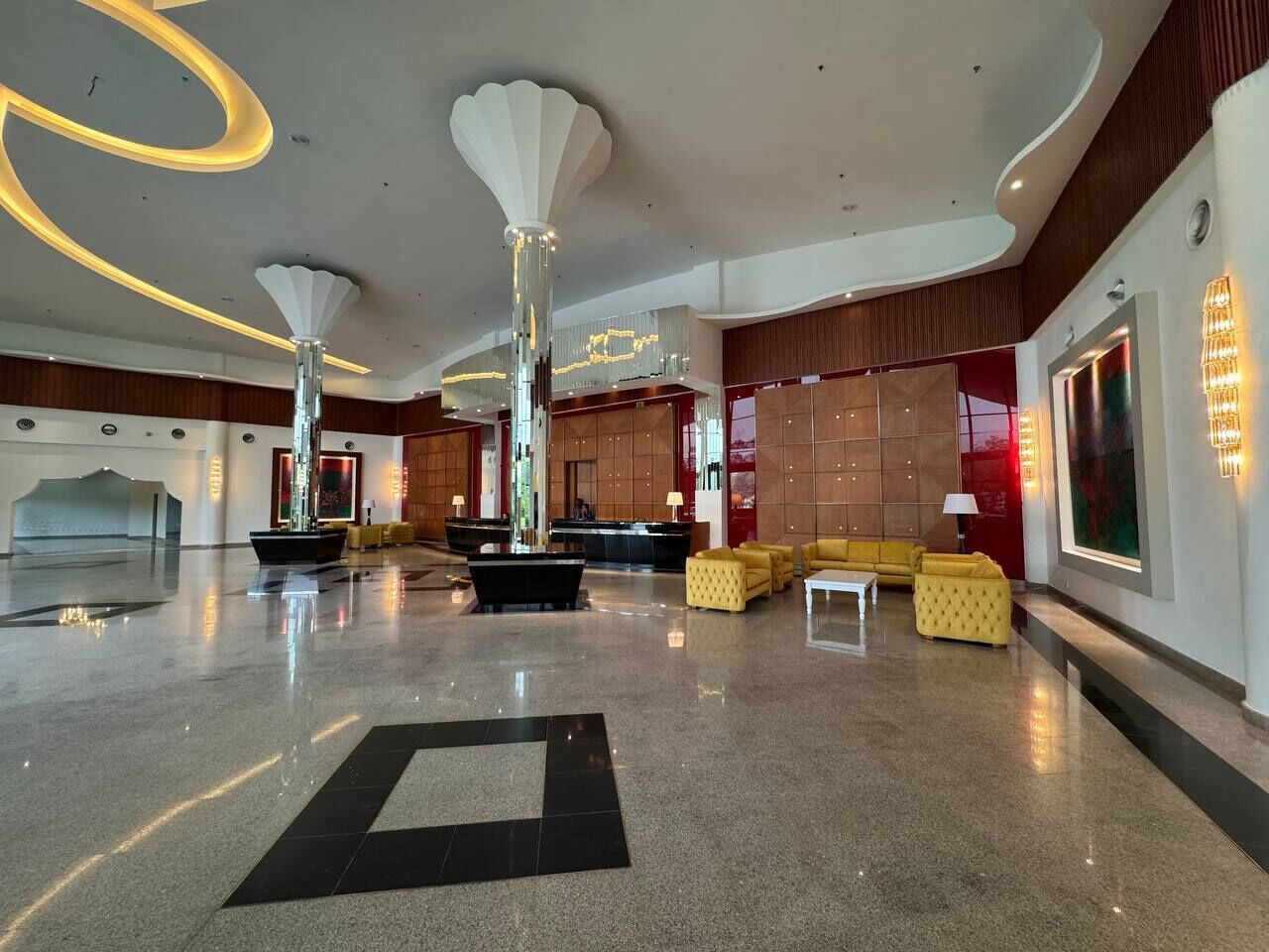A spacious lobby with a polished floor, modern furniture, and distinctive ceiling lighting.