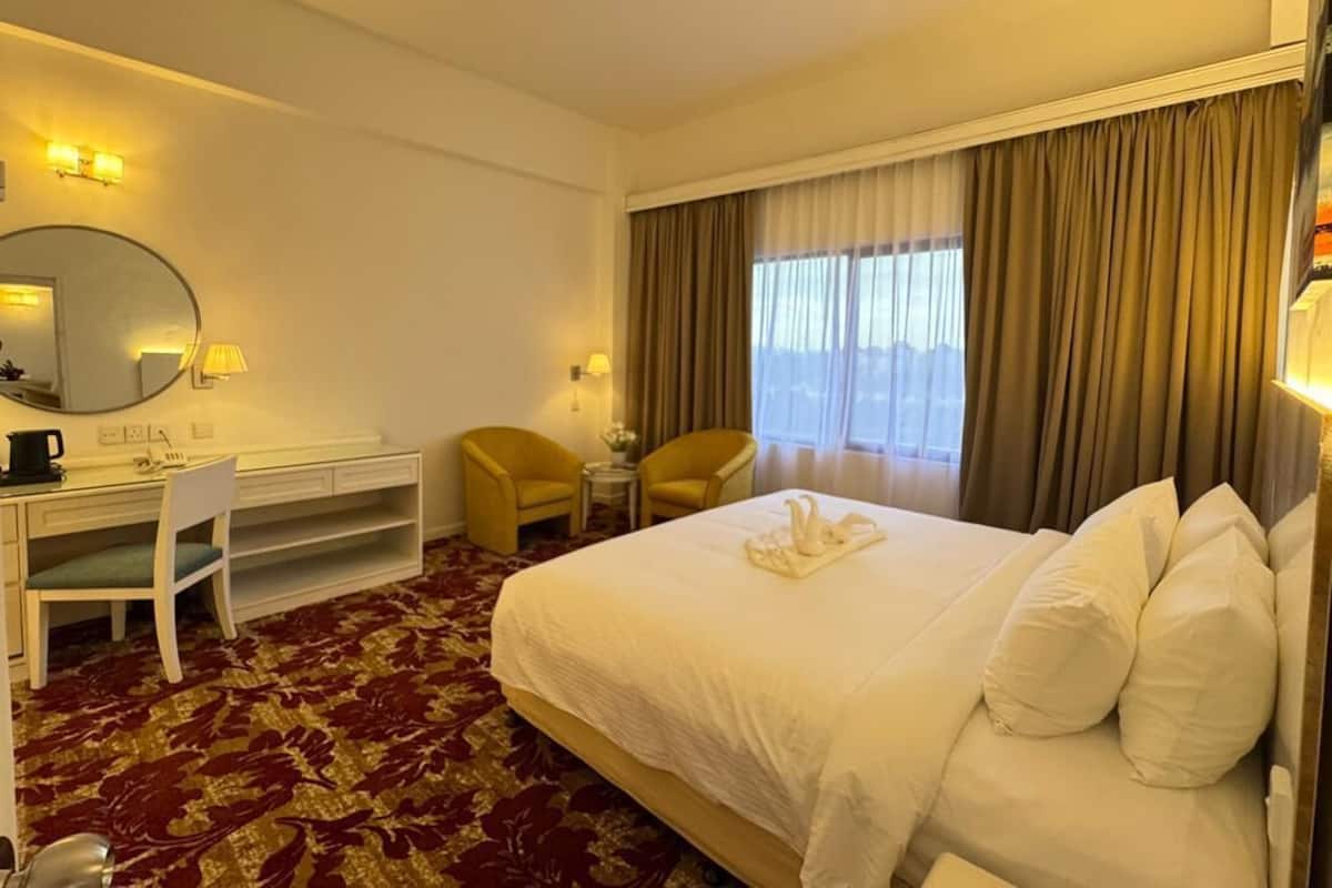 Une chambre d’hôtel avec un grand lit, un bureau, une chaise, une petite table et un miroir.