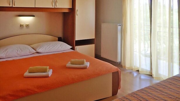 A hotel room with a bed, a radiator, and a window with curtains. - House in Starigrad near Paklenica Park (Starigrad Paklenica)