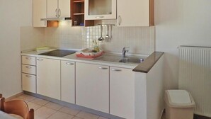A compact kitchen with white cabinets, a stainless steel sink, and a small trash bin. - House in Starigrad near Paklenica Park (Starigrad Paklenica)